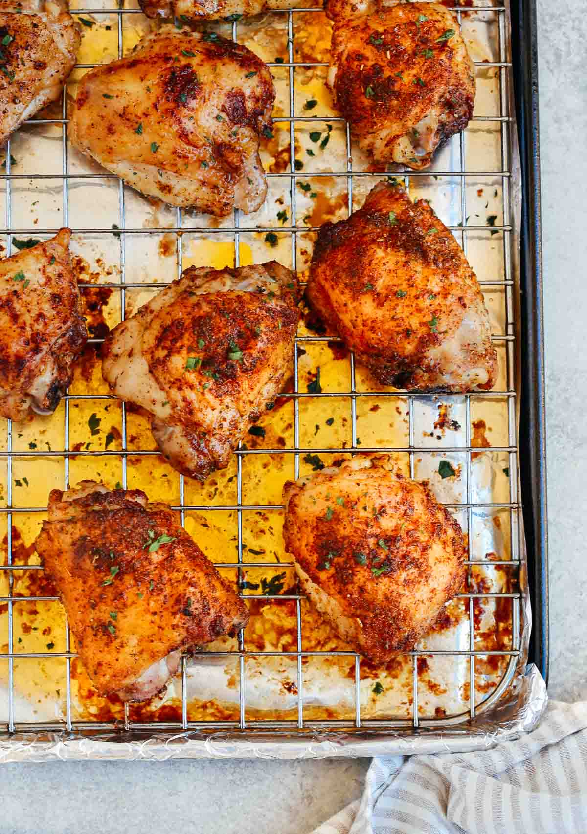 Easy baked chicken thighs cooling on a rack over a sheet pan.