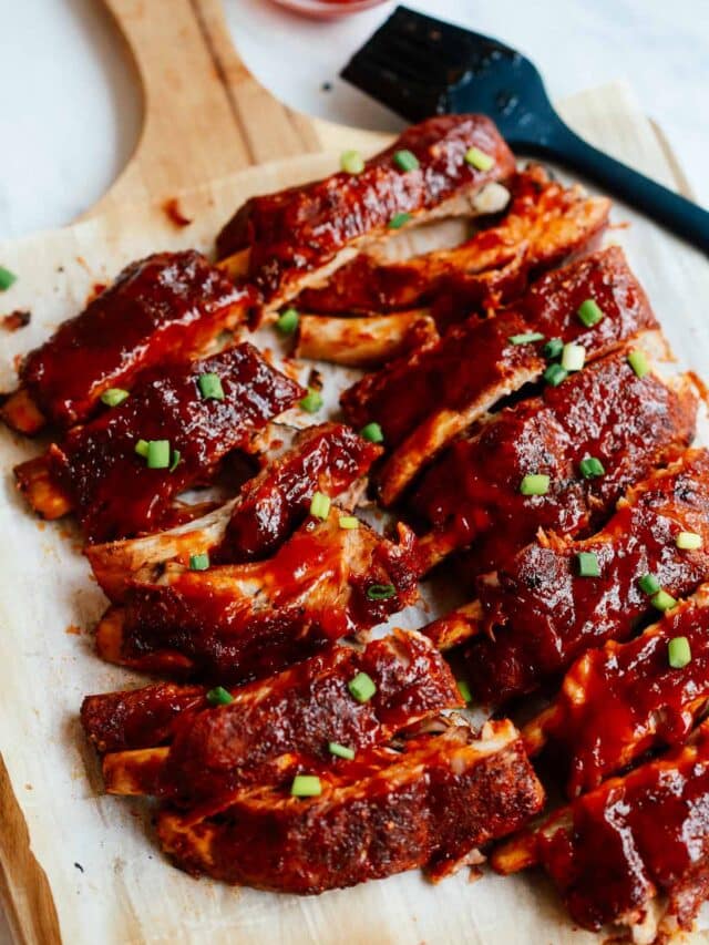 A close up of a baked ribs on a wooden cutting board
