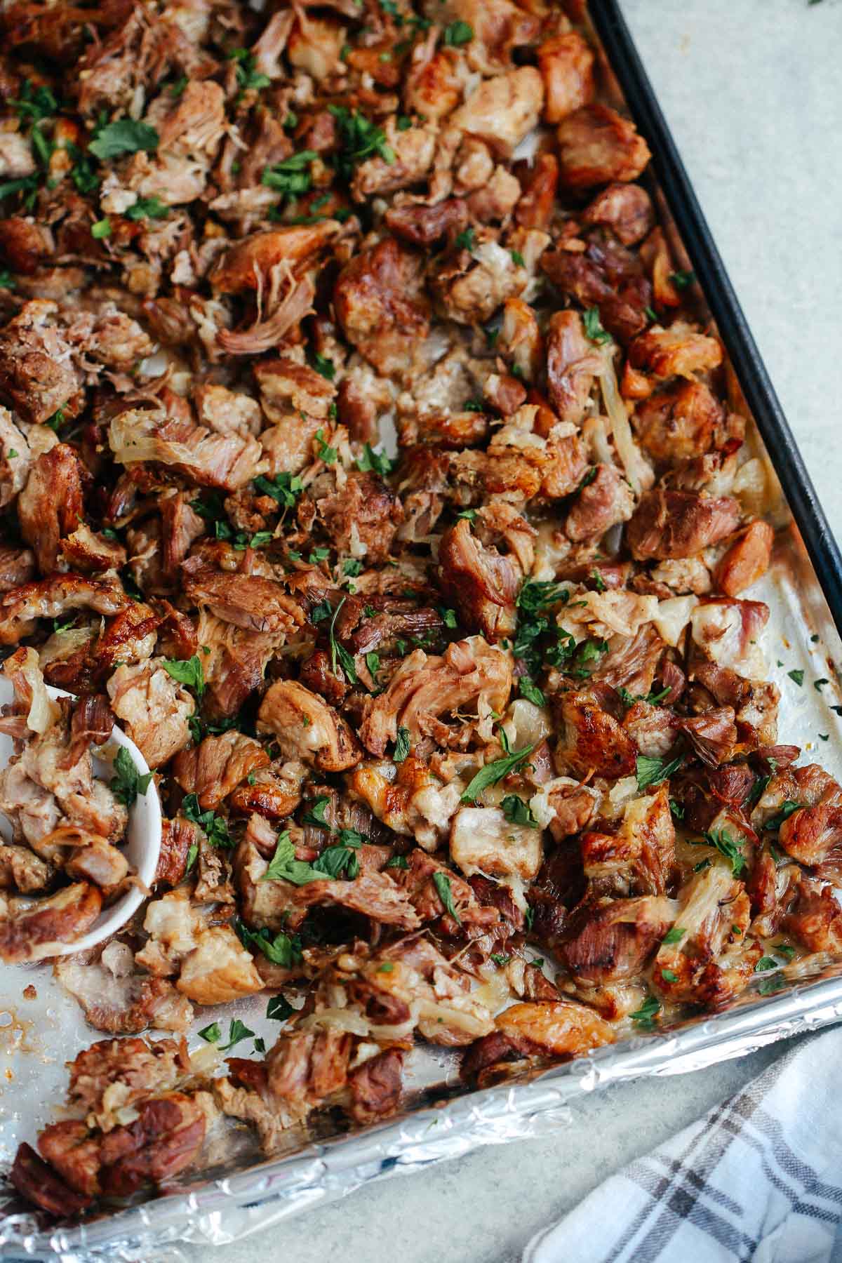 Crispy Instant Pot carnitas on a sheet pan, topped with garnish.