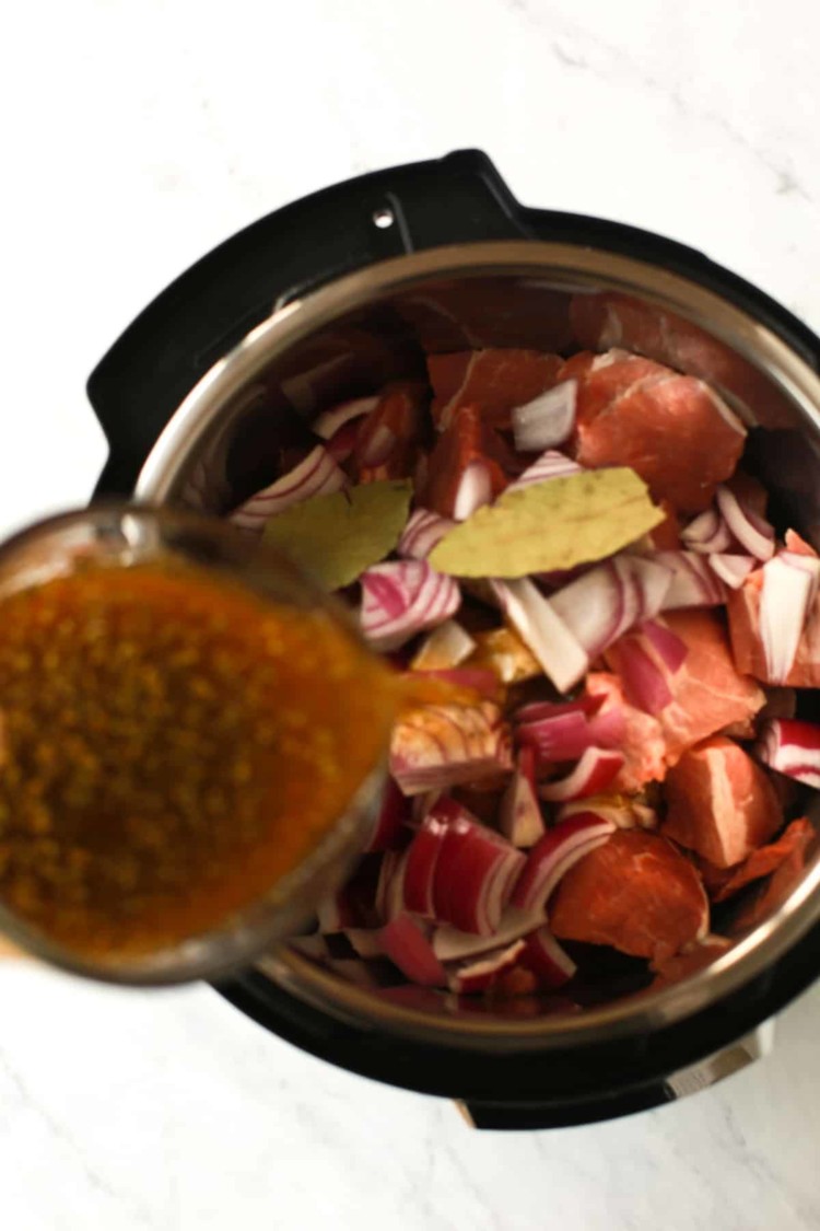 overhead view of beef broth being poured inside of an instant pot