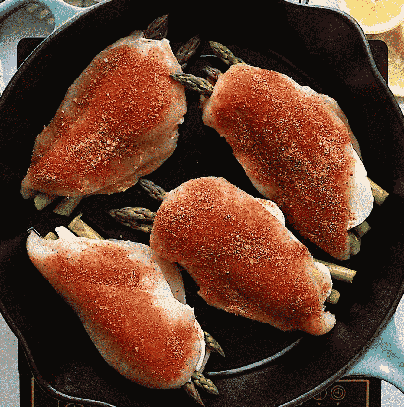 overhead view of a cast iron skillet containing asparagus stuffed chicken breast