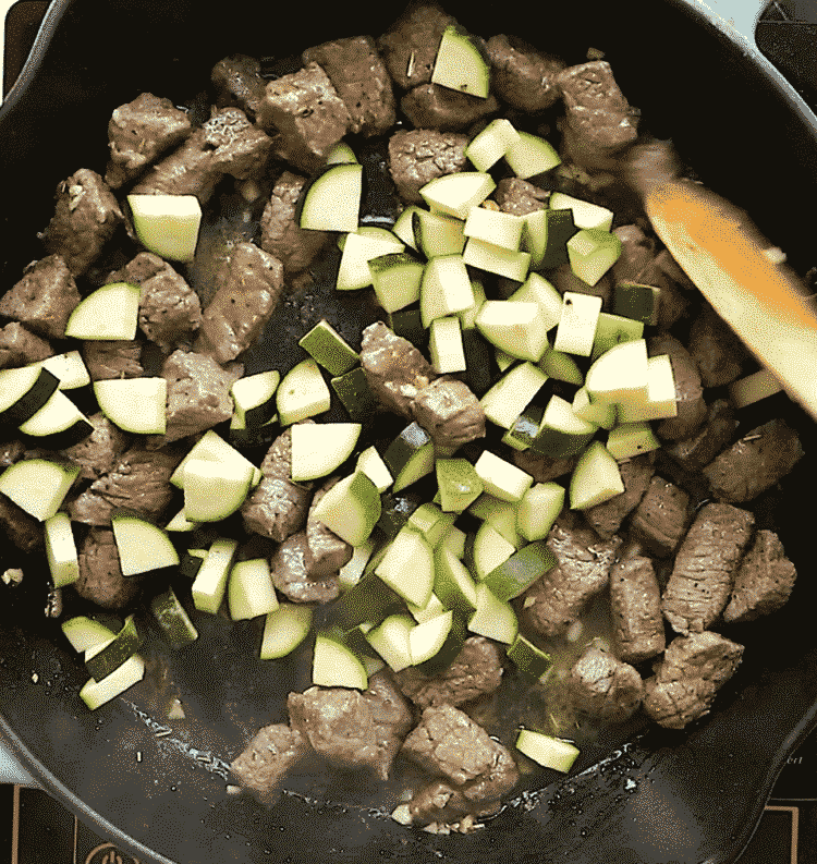 overhead view of a cast iron skillet with diced beef and zucchini