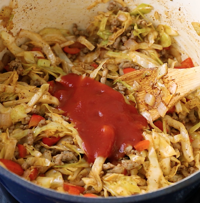 overhead view of cabbage and sausage in a Dutch Oven pan