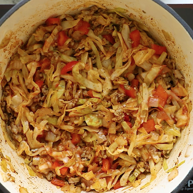 overhead view of cabbage and sausage in a Dutch Oven pan