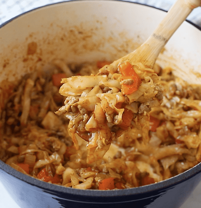 closeup of cabbage and sausage in a Dutch oven pan