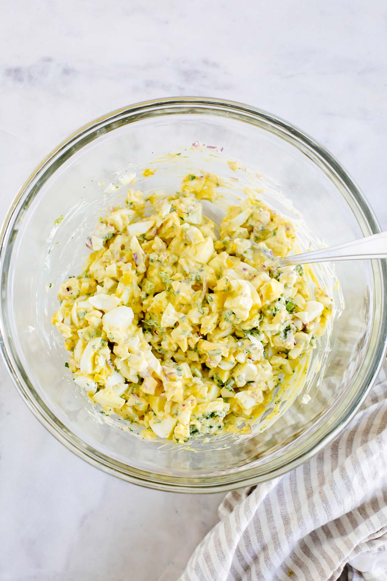 Egg salad being mixed in a bowl.