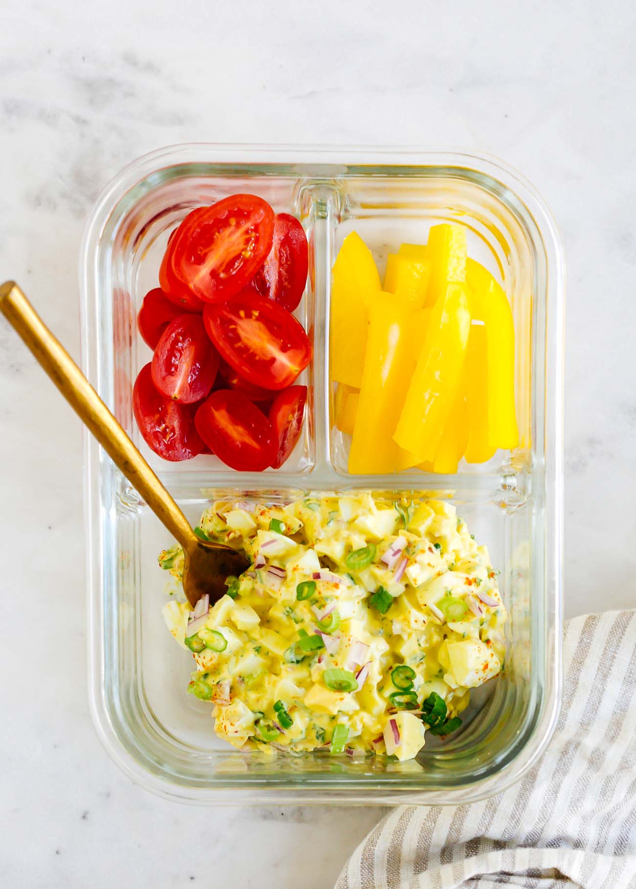 Meal prep container with egg salad, cherry tomatoes, and bell peppers.