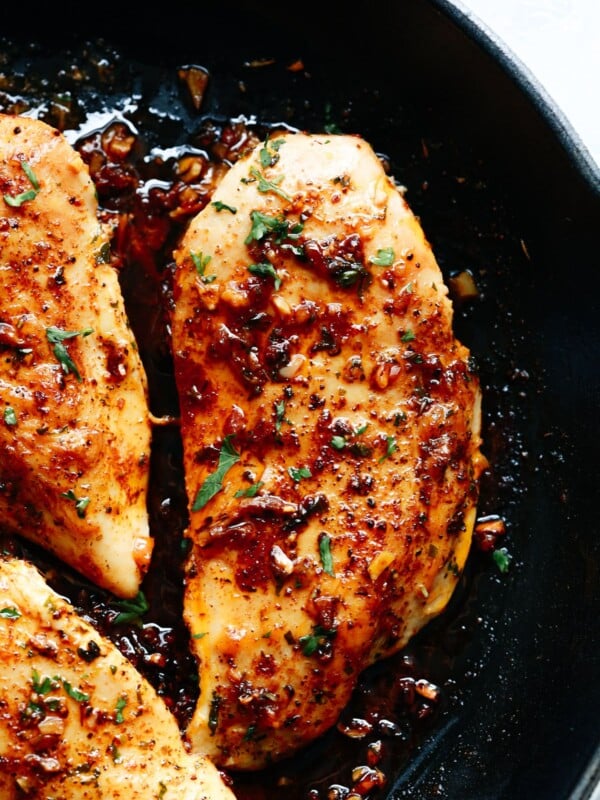 Seared chicken breasts cooked in a skillet with a garlic herb glaze.