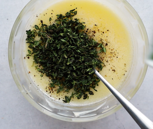 overhead view of melted butter and herbs in a small glass bowl