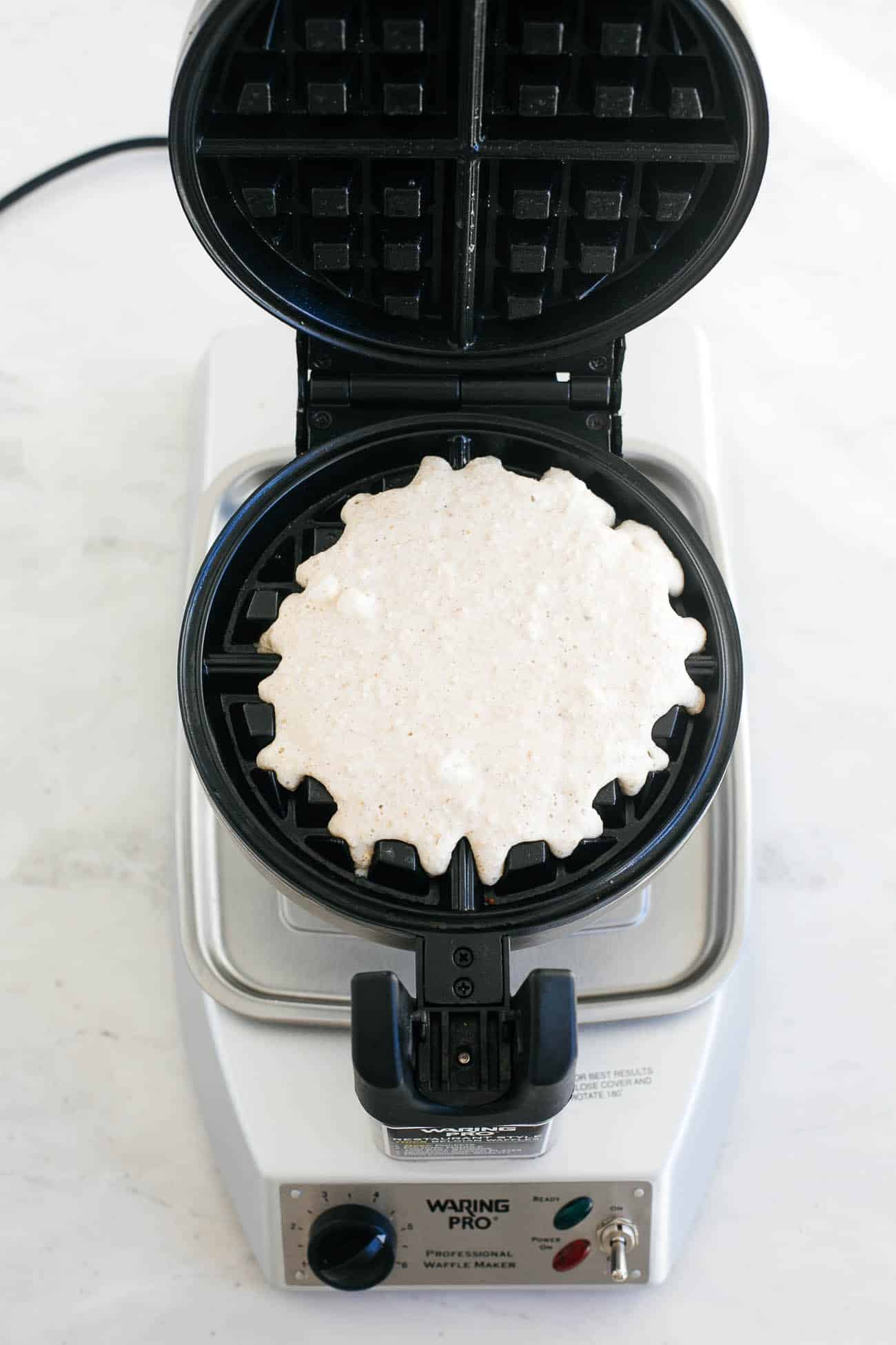 Batter going into a waffle maker.