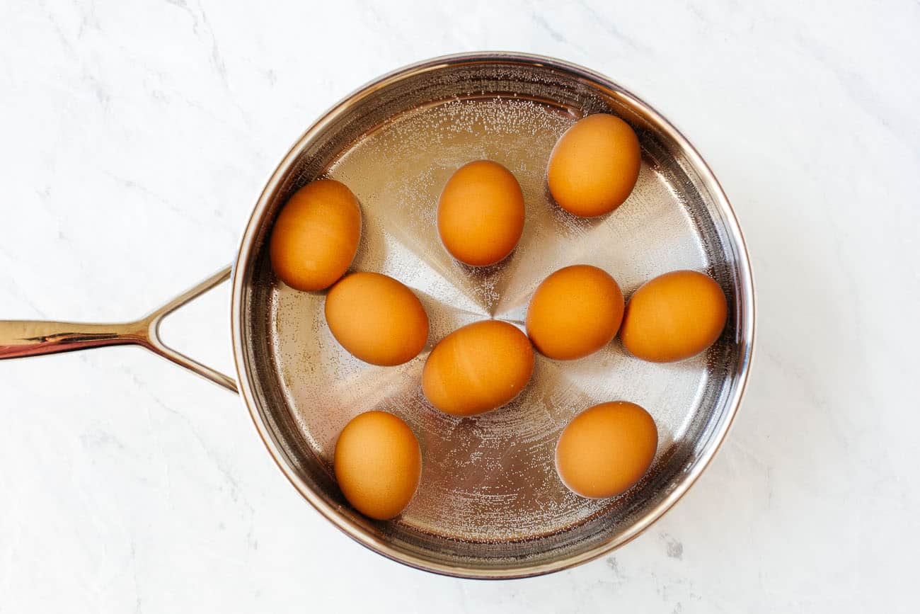 Eggs inside of a pot of water to be boiled.