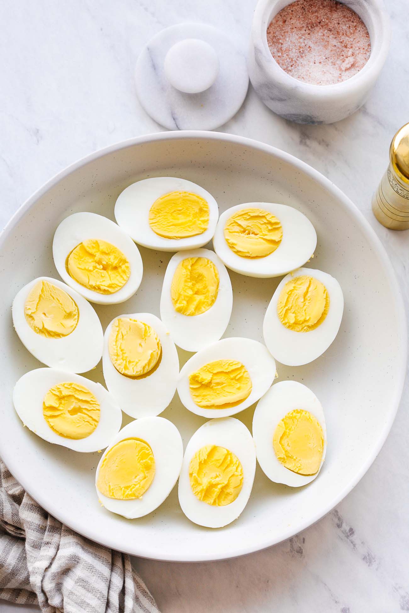 A plate with 12 halves of hard boiled eggs.