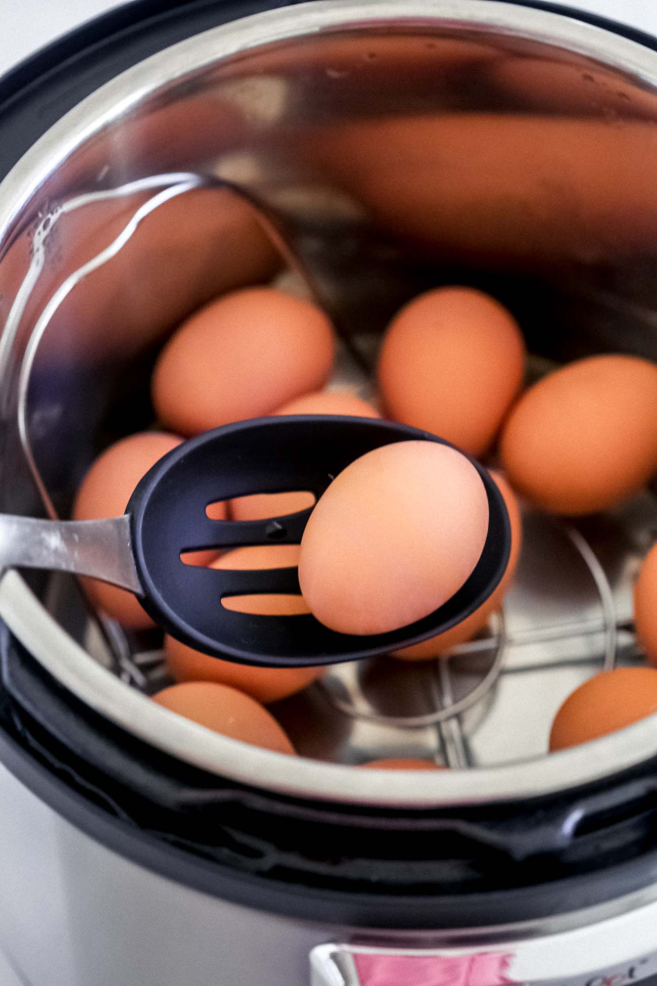 Using a slotted spoon to remove hard boiled eggs in the Instant Pot.