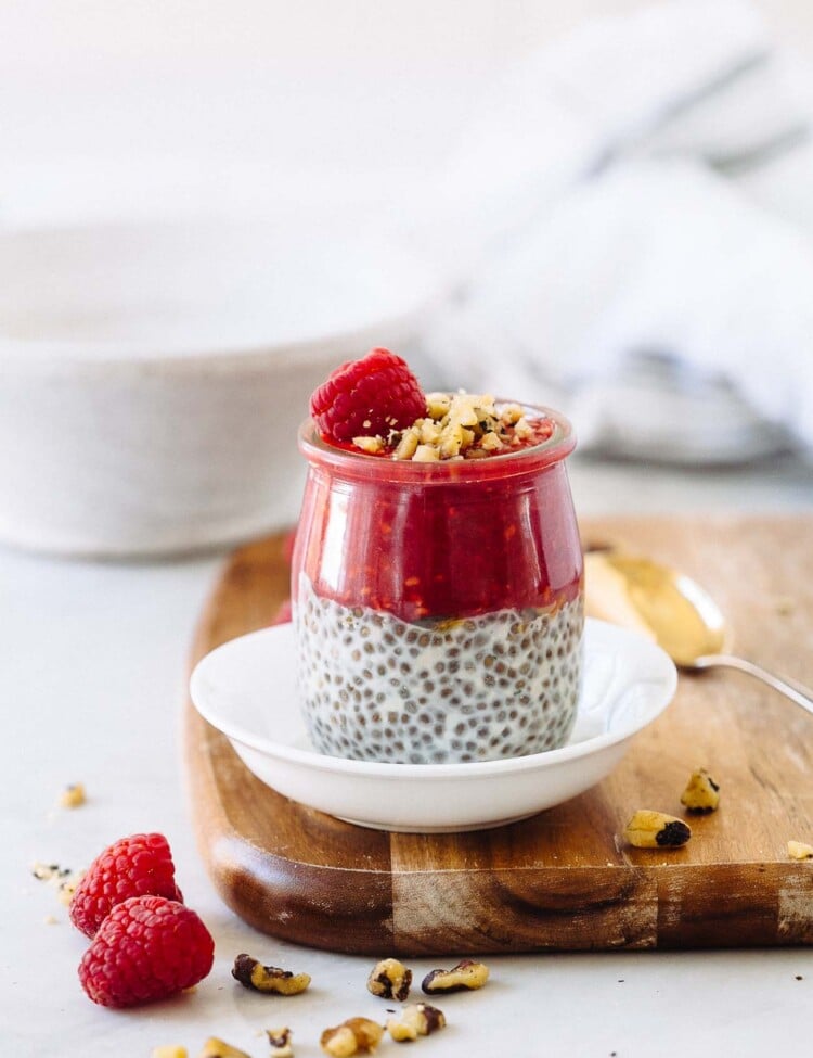 A jar of chia seed pudding with raspberry puree, raspberry, and pistachios on top.