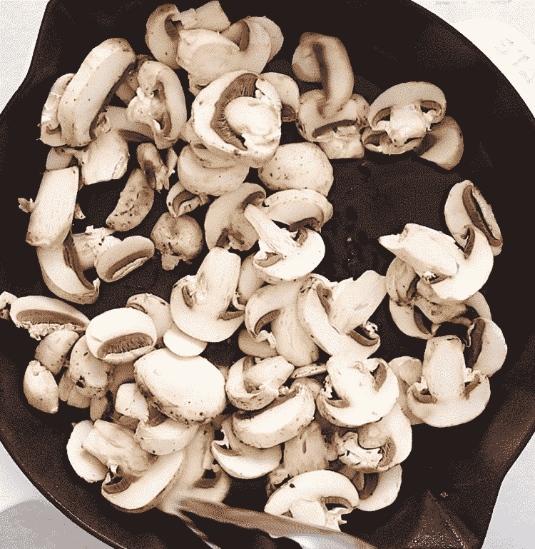 overhead view of sliced mushrooms in a cast iron skillet