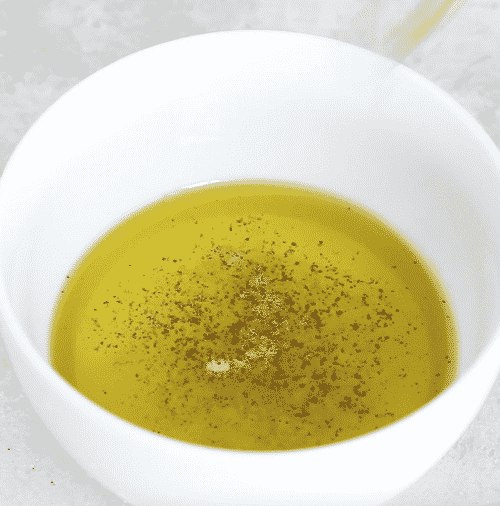 closeup of a small white bowl containing mediterranean salad dressing