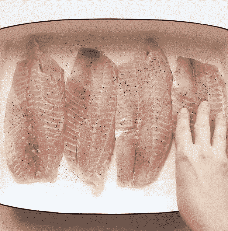 overhead view of a baking sheet containing tilapia fillets