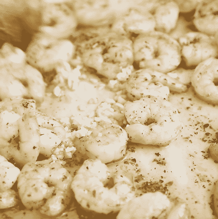 closeup of shrimp with garlic and butter in a white skillet