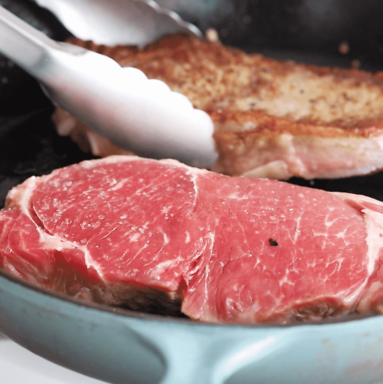 close up view of steaks in a cast iron skillet