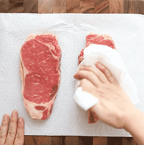 overhead view of raw steak on a wooden board