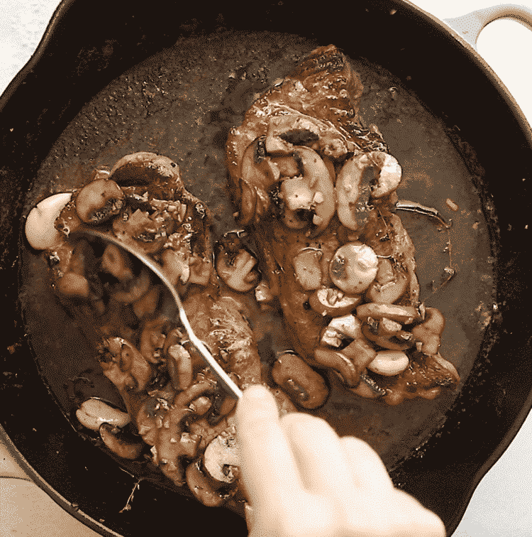 overhead view of steak with mushroom in a cast iron skillet