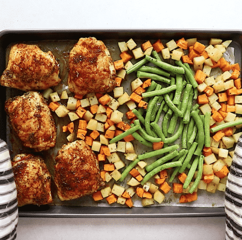 overhead view of chicken with vegetables on a baking sheet