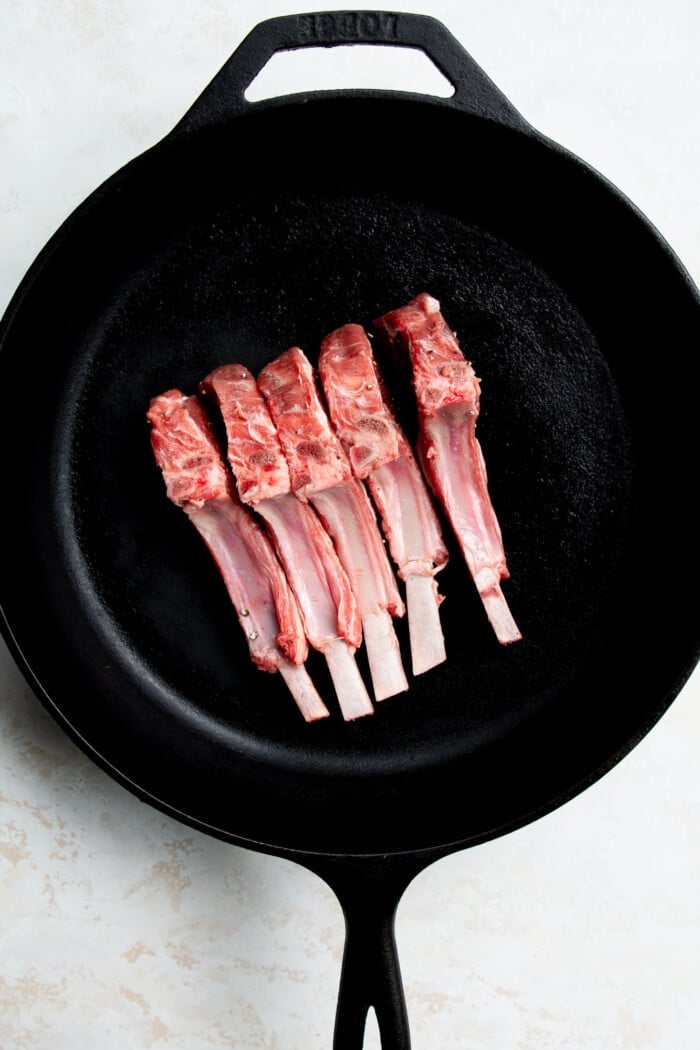 raw lamb chops in a cast iron skillet