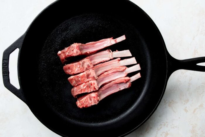 raw lamb chops in a cast iron skillet