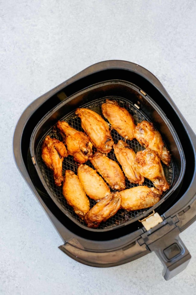 overhead view of an air fryer basket containing cooked chicken wings