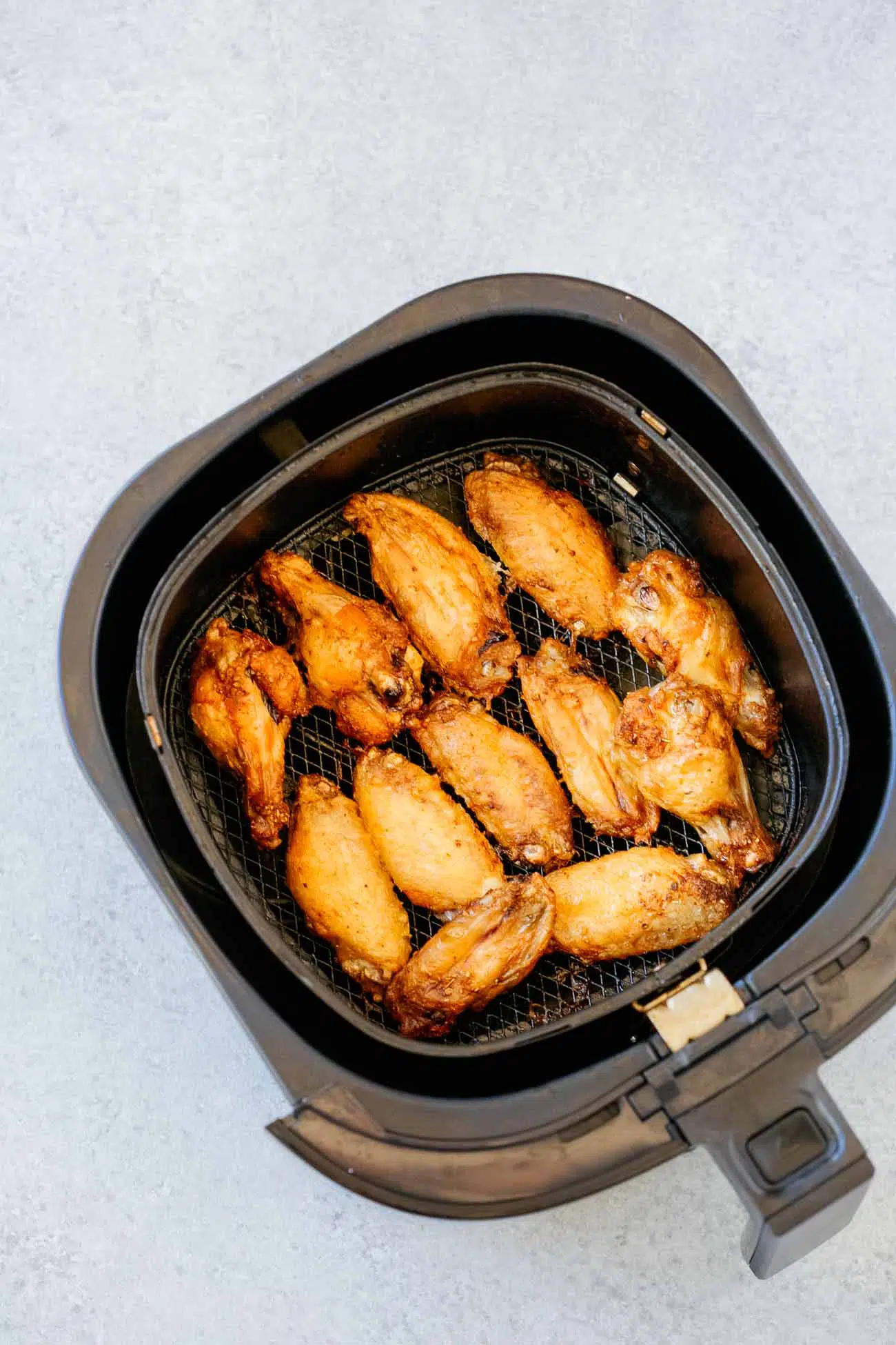 Air fryer basket with chicken wings.