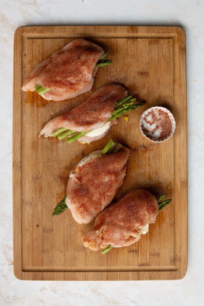 seasoned chicken breasts on a wooden board.