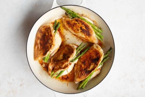 asparagus stuffed chicken breast inside os a white skillet