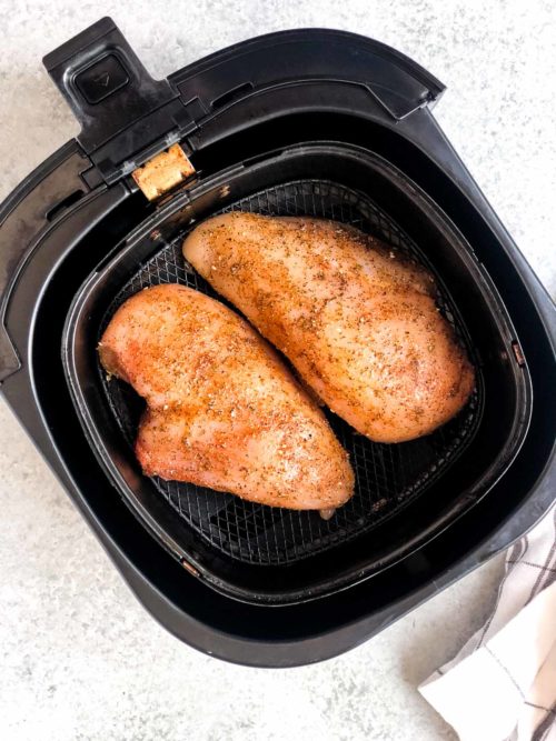 overhead view of 2 chicken breasts inside of an air fryer
