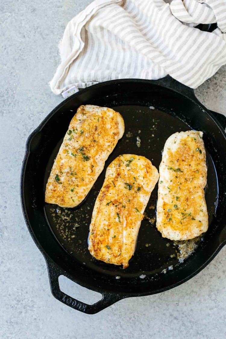 overhead view of garlic butter halibut fish in a cast iron skillet