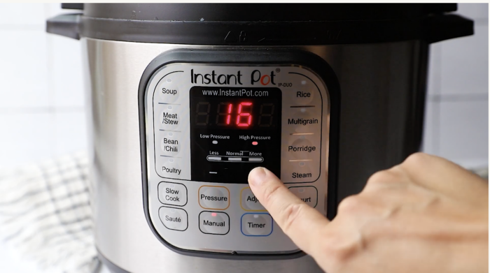 A hand presses a button on the front panel of an Instant Pot pressure cooker, which displays the number 16 on its digital screen—perfectly set for preparing a hearty Instant Pot Beef Stew.