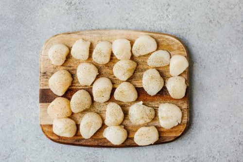 overhead view of raw scallops on a wooden board