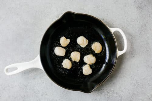 overhead view of raw scallops in a cast iron skillet