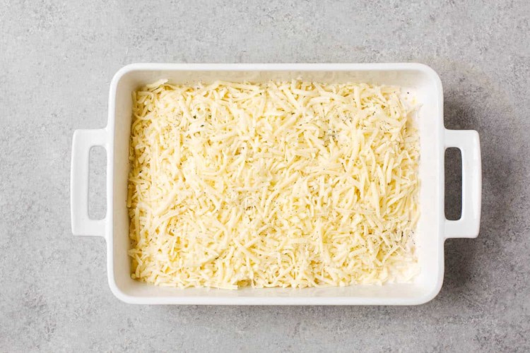 overhead view of white casserole containing sliced potato, milk and mozzarella cheese