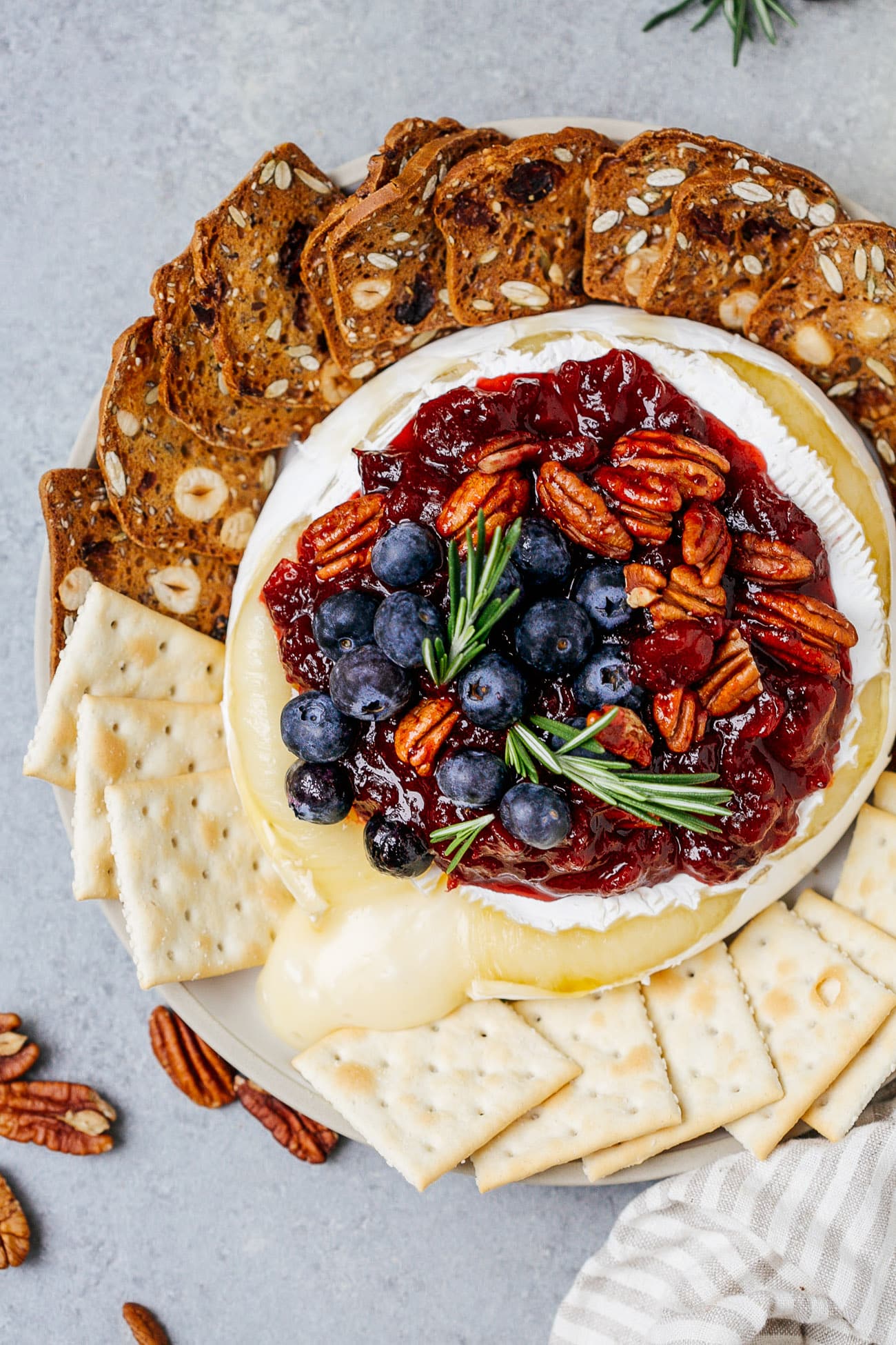 Overhead view of a baked brie with cranberry sauce served with crackers.