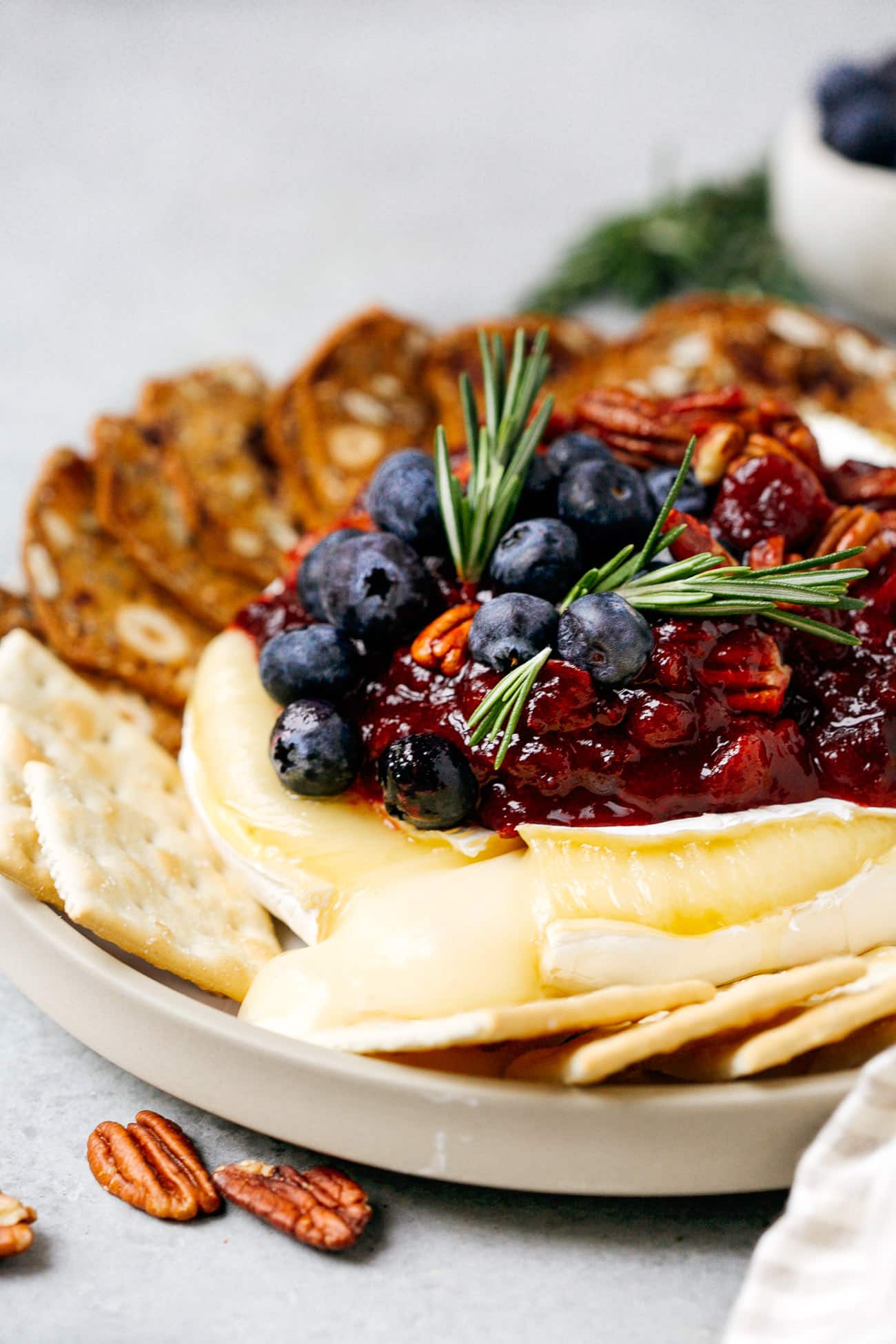 Close up of a baked brie with cranberry sauce cut open with cheese melting out.