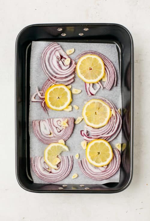 baking sheet with slices of red onions and lemon