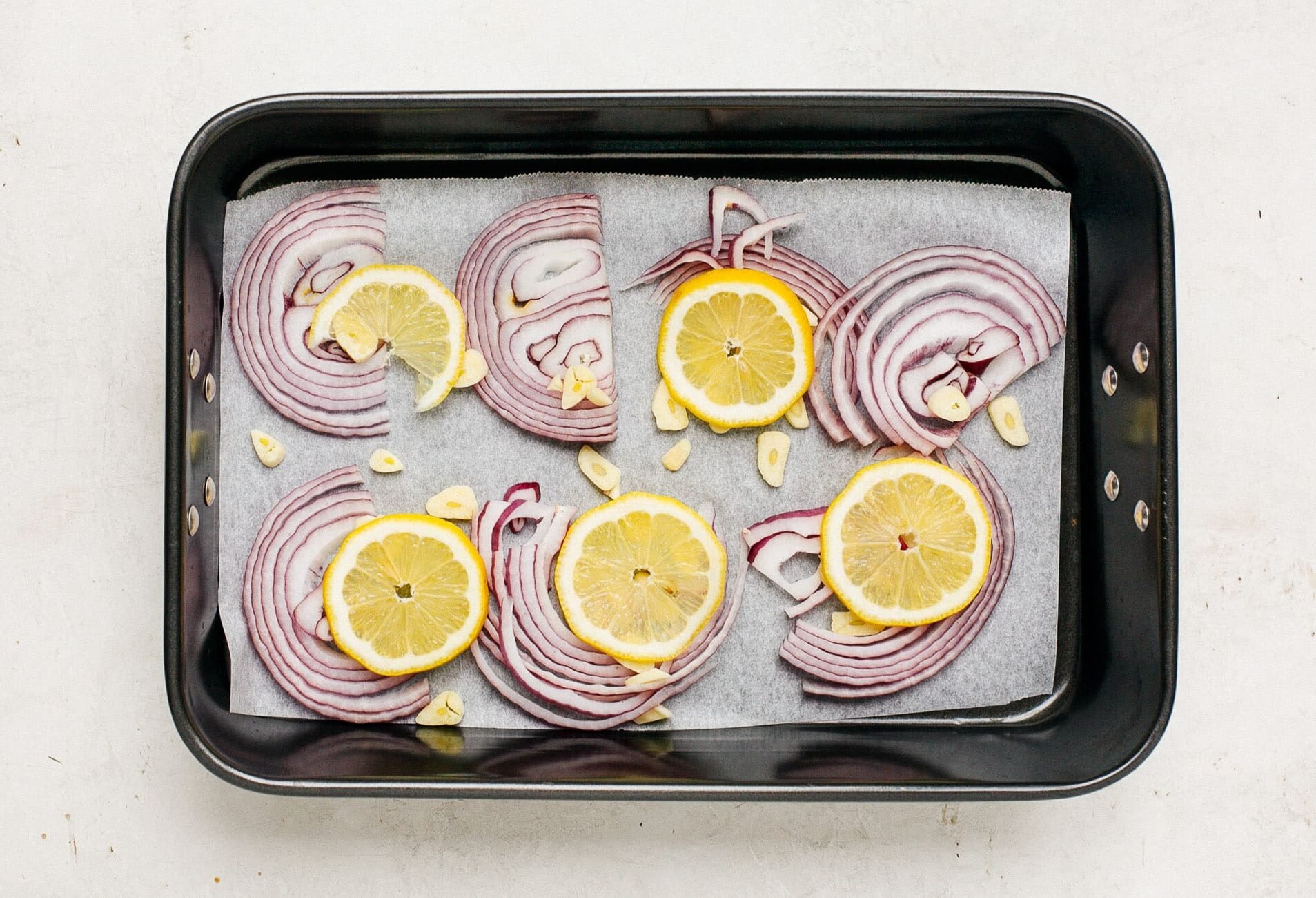 baking sheet with slices of red onions and lemon