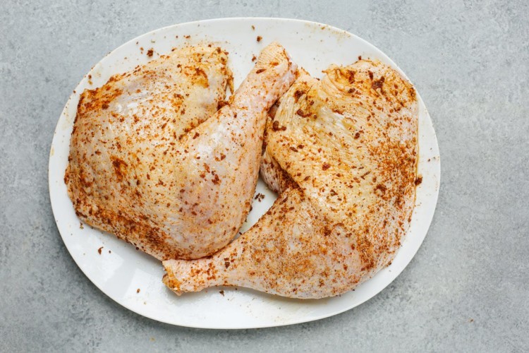 seasoned raw turkey leg on a white plate