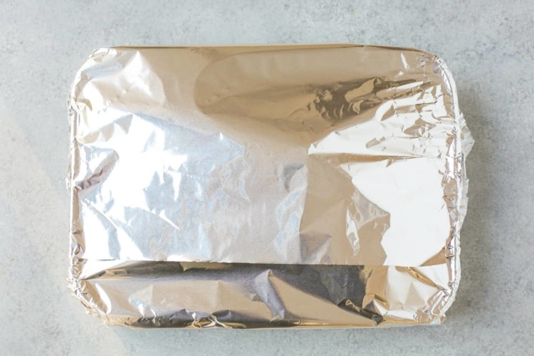 leg of lamb on a roasting pan wrapped with aluminium foil