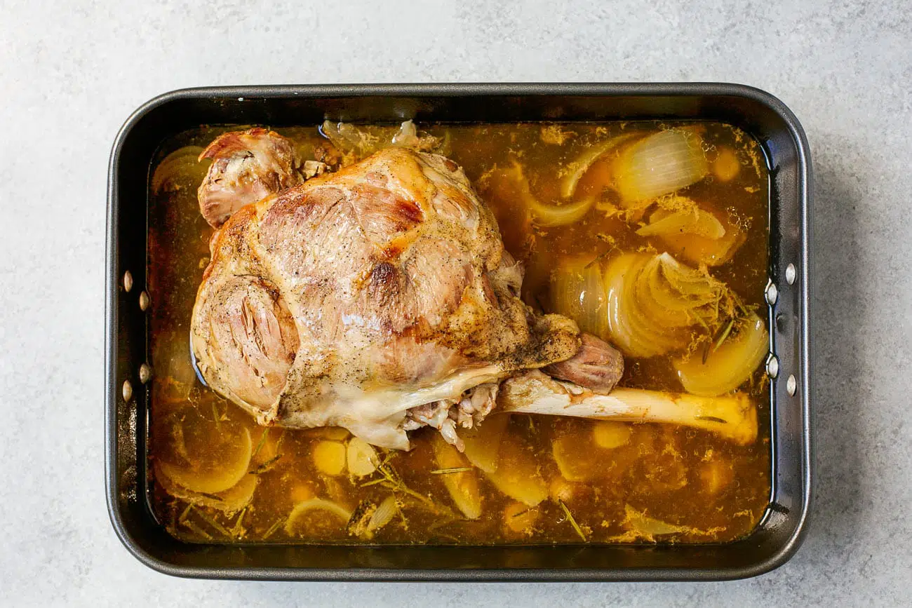 cooked leg of lamb in a roasting pan