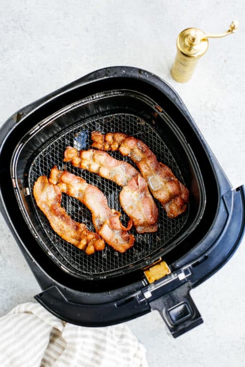 overhead view of cooked bacon inside of a air fryer basket