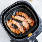 overhead view of cooked bacon inside of a air fryer basket