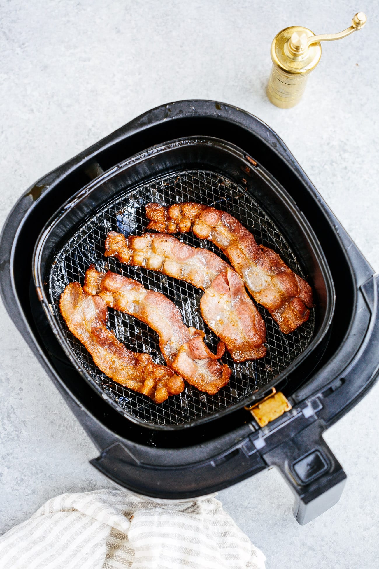 overhead view of cooked bacon inside of a air fryer basket 