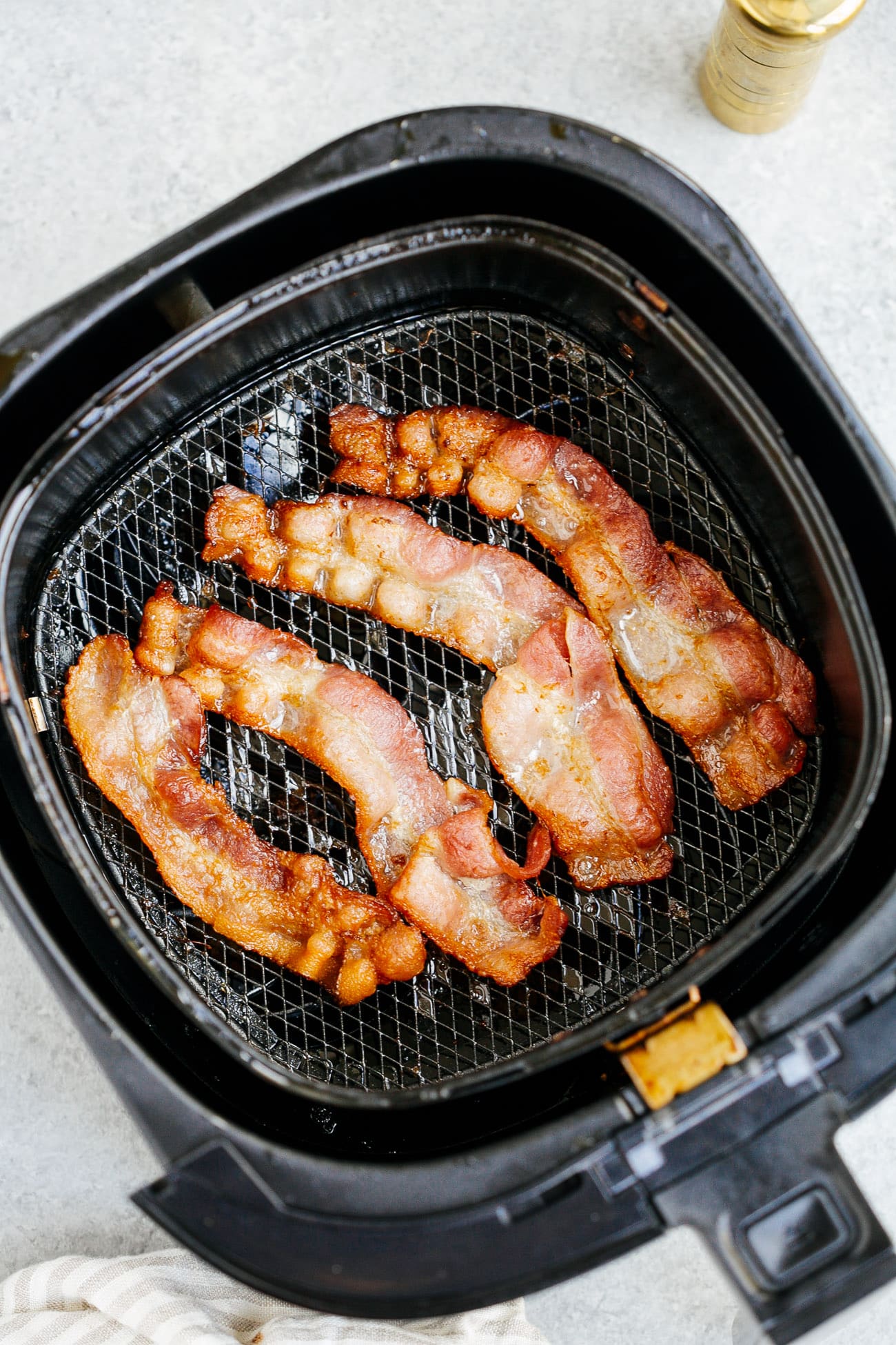 overhead view of cooked bacon inside of a air fryer basket 