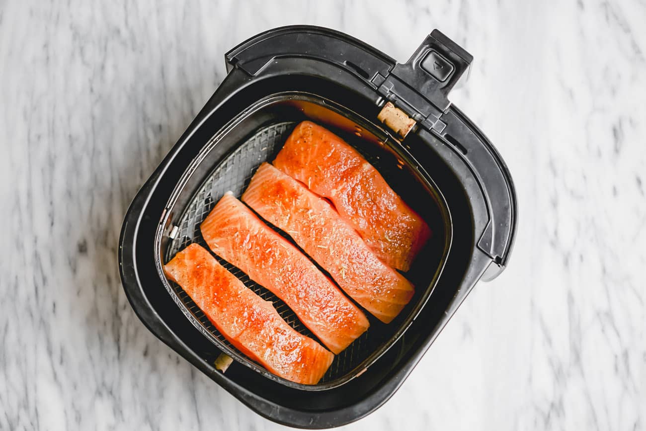 overhead view of air fryer basket containing raw salmon 